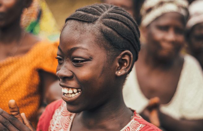 Girl smiling and clapping amongst a large group of people