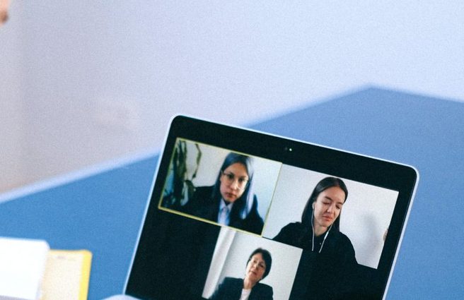 Person on a video call looking at laptop with three other participants
