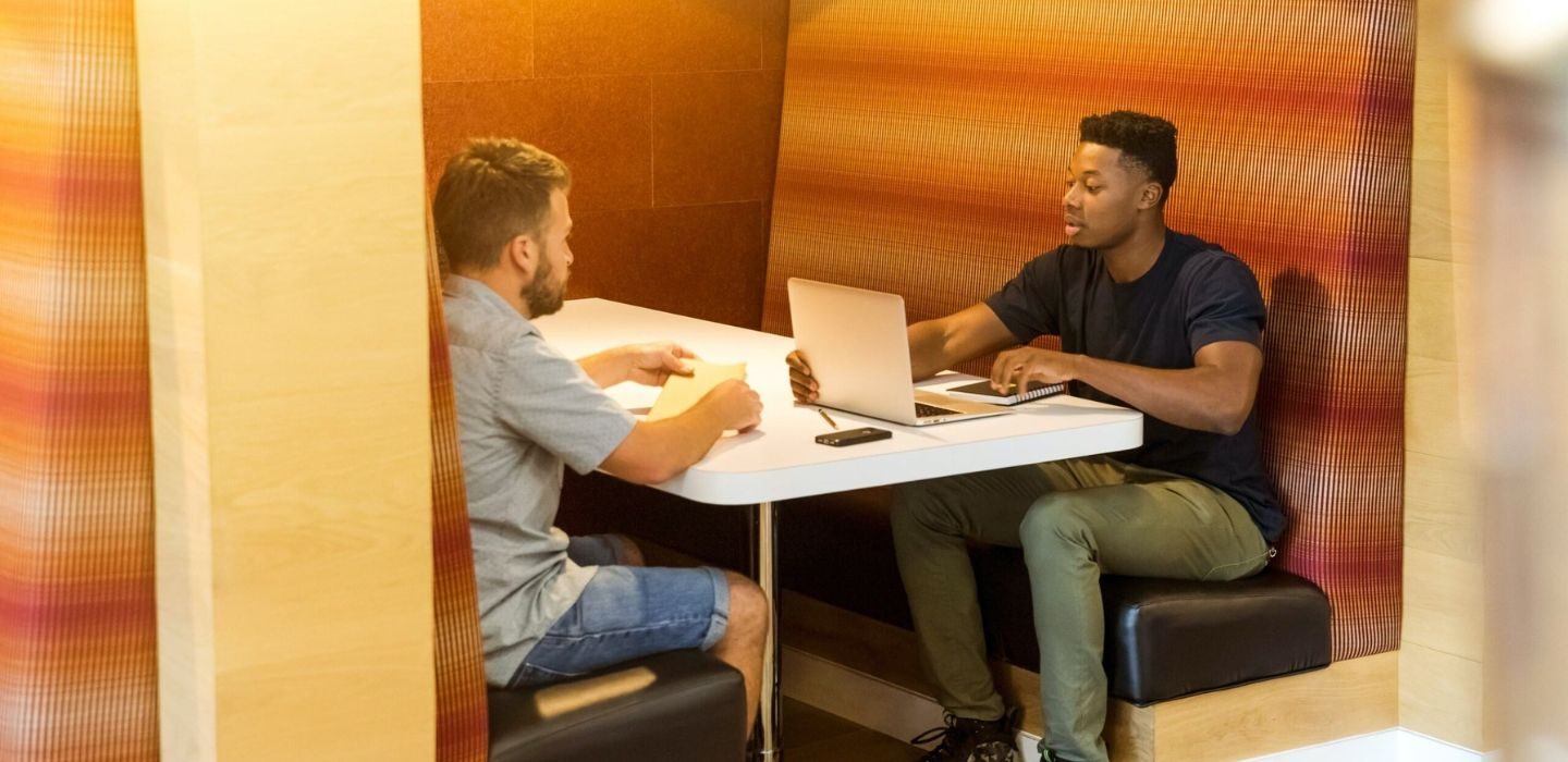 Two people in an orange booth studying