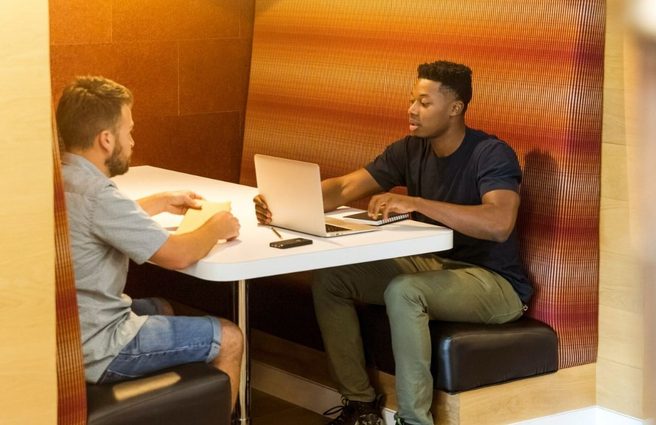 Two people in an orange booth studying