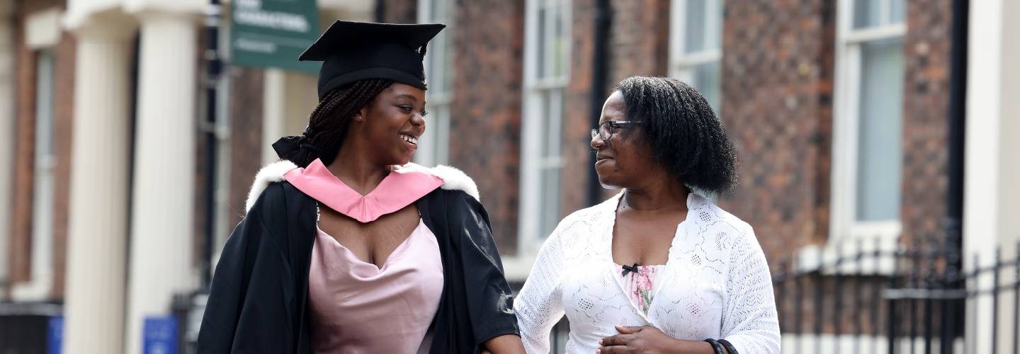 Graduate in cap and gown smiling at friend