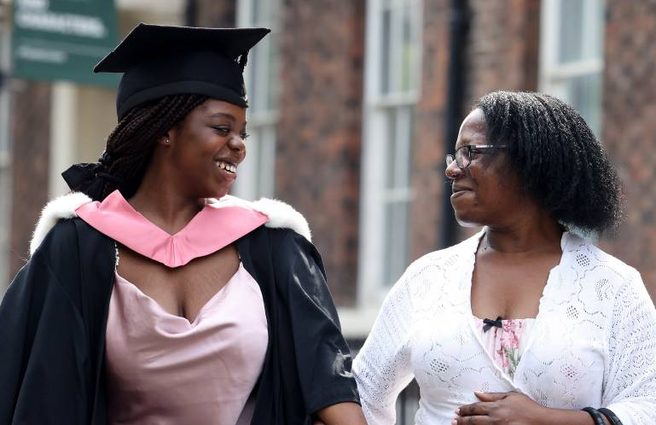 Graduate in cap and gown smiling at friend
